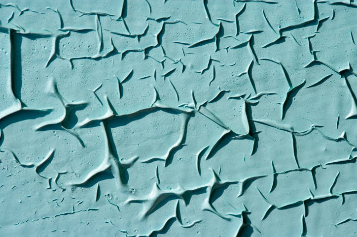 close-up of a turquoise cracked and peeling painted background, showing texture and abstract patterns
